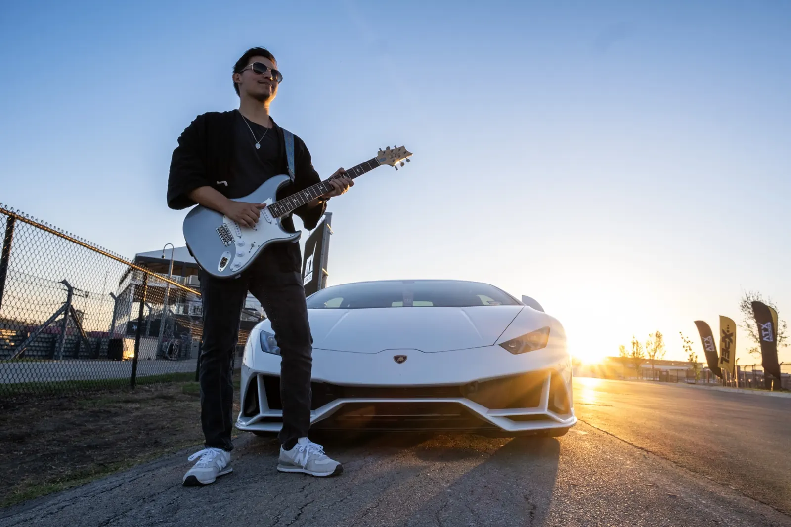 Live electric guitarist at sunset beside a white supercar at an Austin supercar event