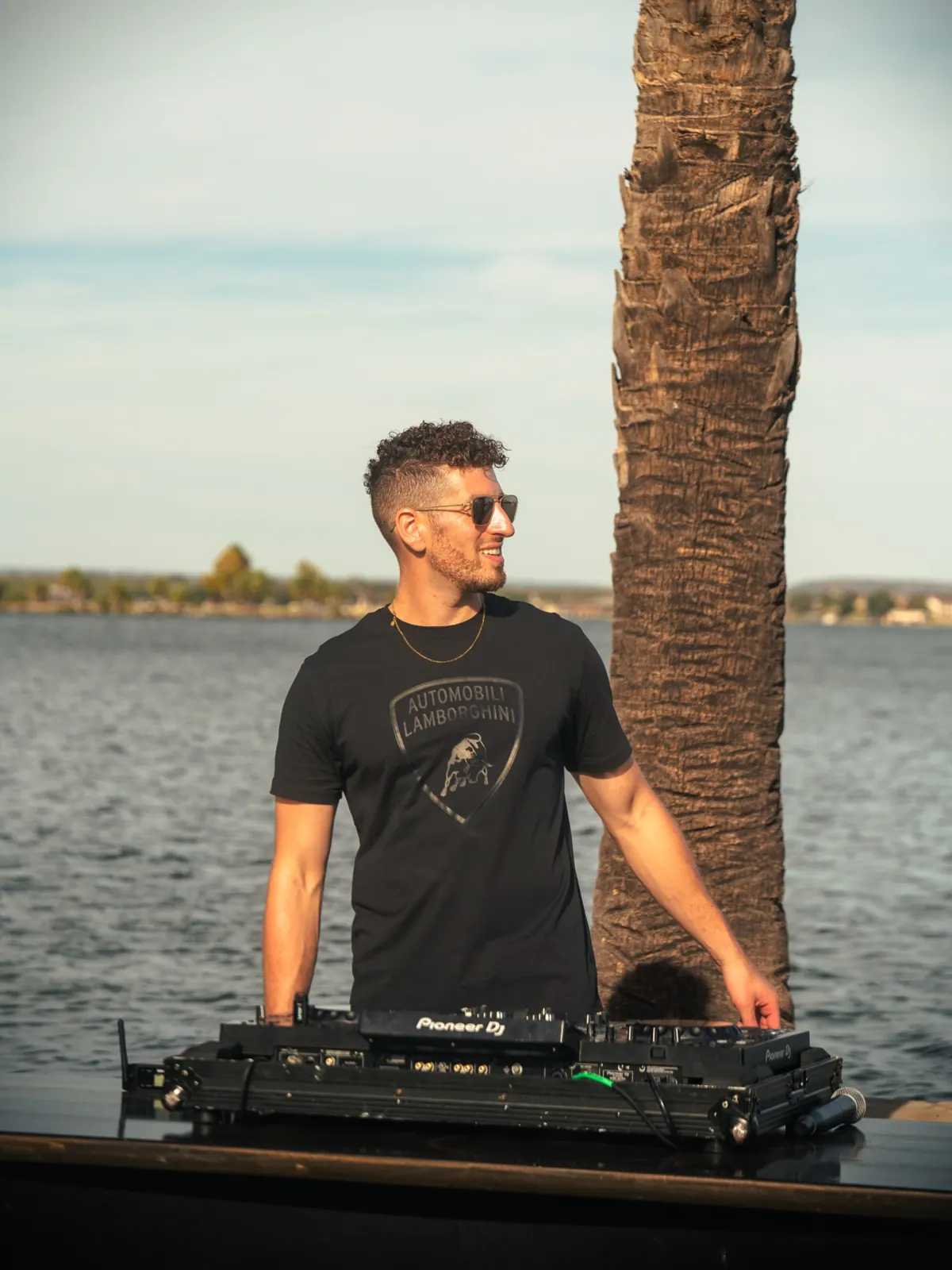 DJ Jordan Miller at the decks by the water during a Lamborghini Austin event
