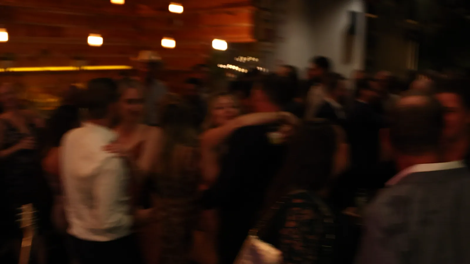 Guests dancing close together on a dimly lit wedding reception dance floor