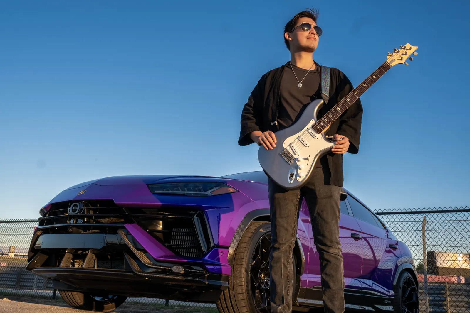 Live electric guitarist performing beside a purple Lamborghini at an Austin supercar event