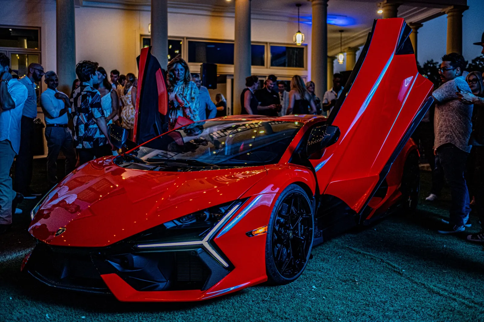Orange Lamborghini Revuelto with its scissor doors raised at the Revuelto launch party in Austin, where DJ Jordan Miller performed