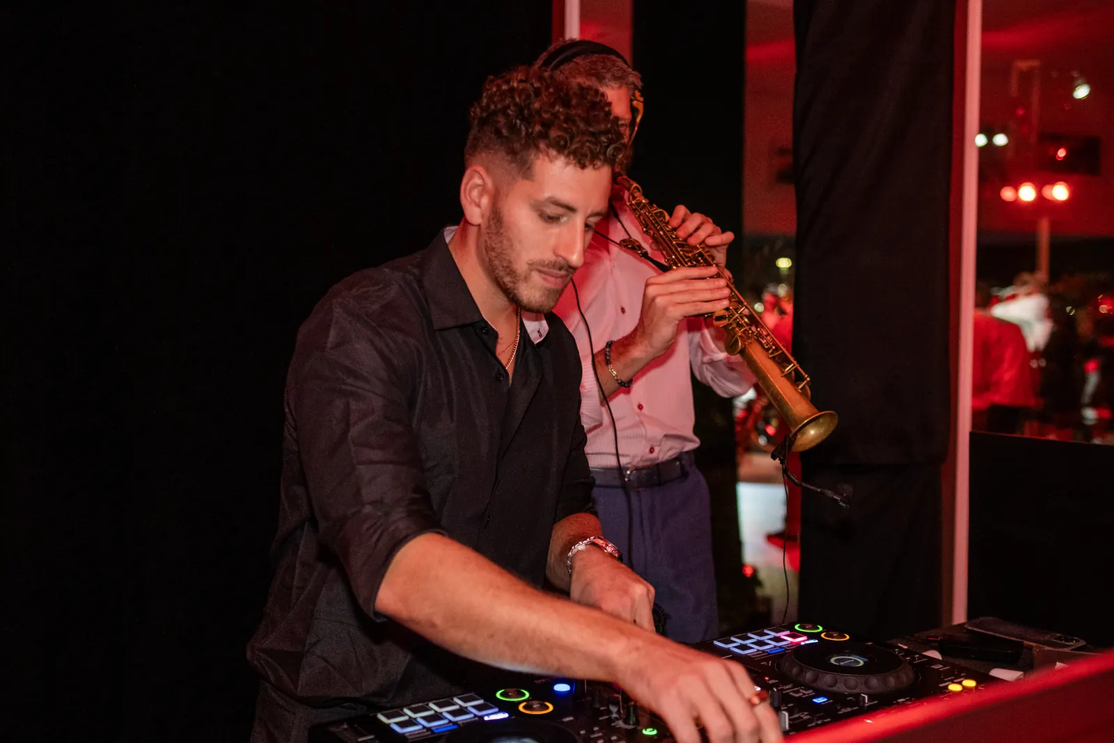 DJ Jordan Miller mixing while a live saxophonist plays soprano sax behind him at the Ferrari SF90 XX Stradale reveal in Austin